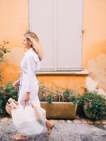 Lucy in front of a pink wall and pale blue shutters, bougainvillea spilling over