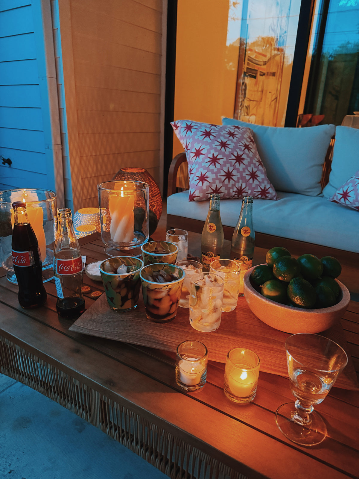 Candles, limes and drinks laid out on a ledge by the pool at dusk