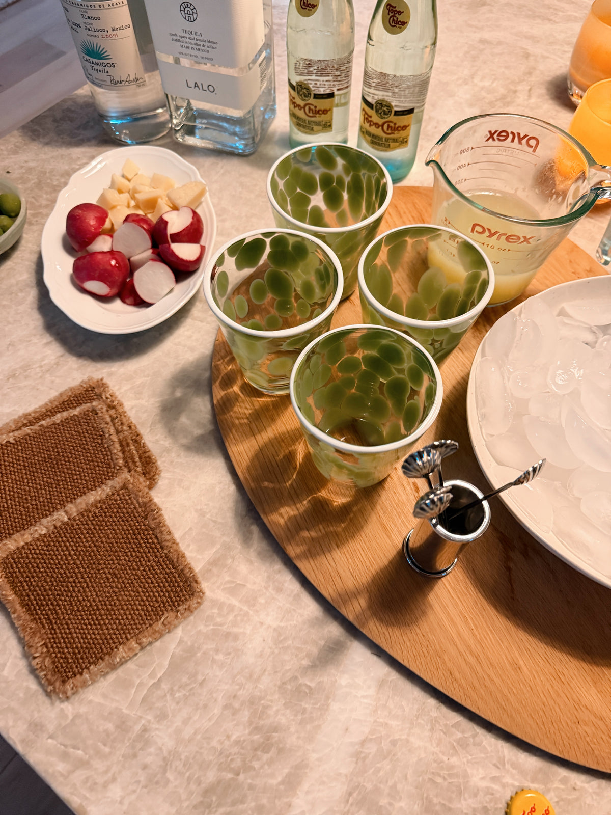 Glasses of ranch water on a round tray beside a plate of radishes