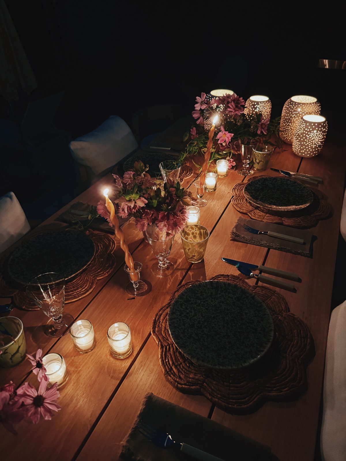 Candlelit table at night with flowers and woven chargers