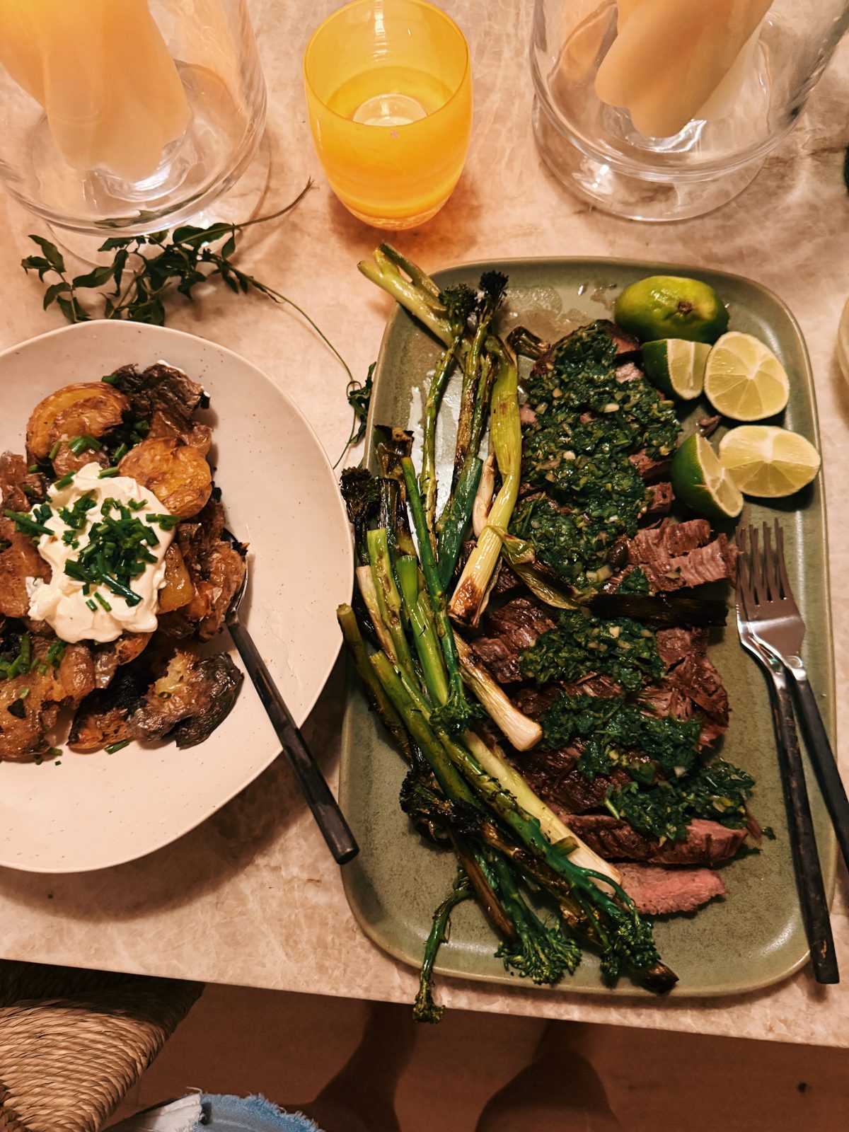 A plate of smashed potatoes with crema beside the steak platter and orange drinks