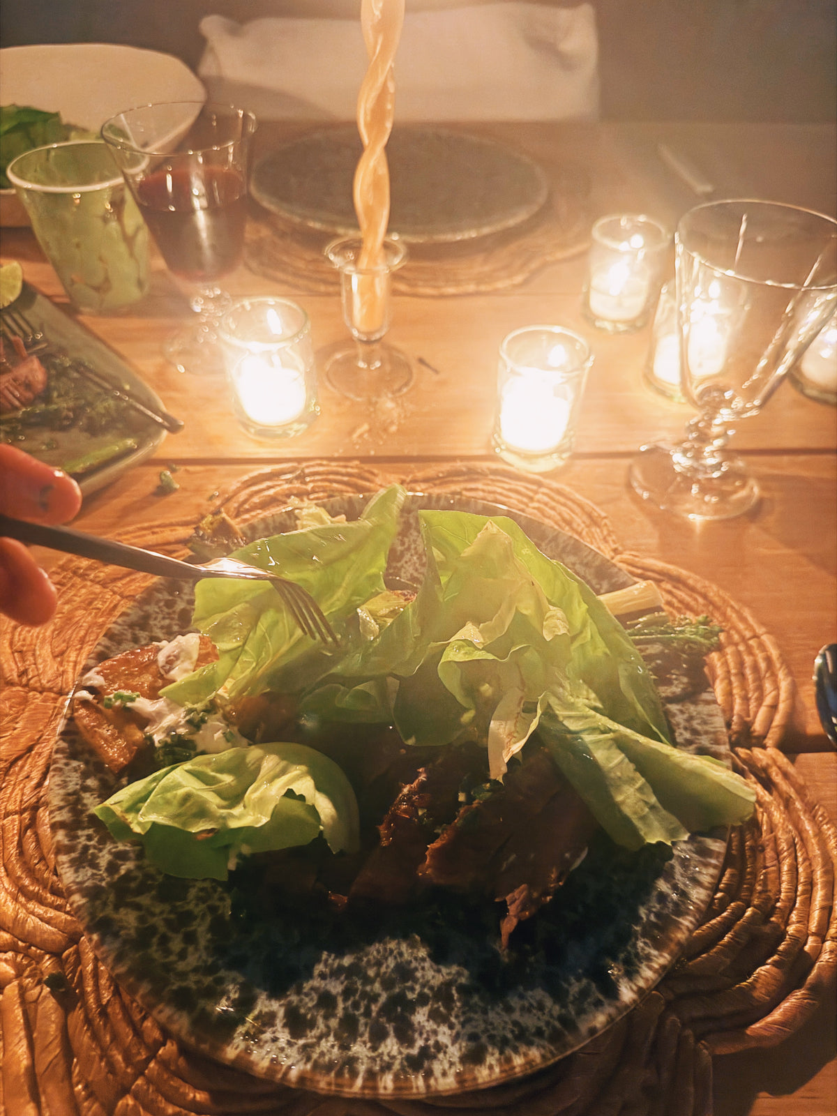 A bowl of butter lettuce on the candlelit table