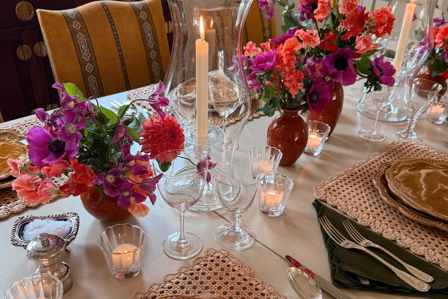 A table laid with marbled plates, hurricanes and pink and orange flowers
