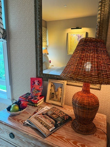 The guest-room chest: a wicker lamp on, magazines, books and a bowl of fruit