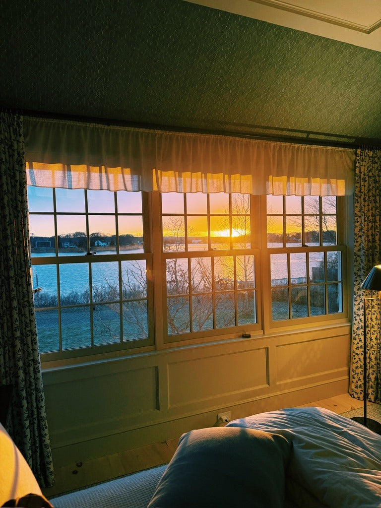 The guest room at sunset, the water through the window and the bed turned down