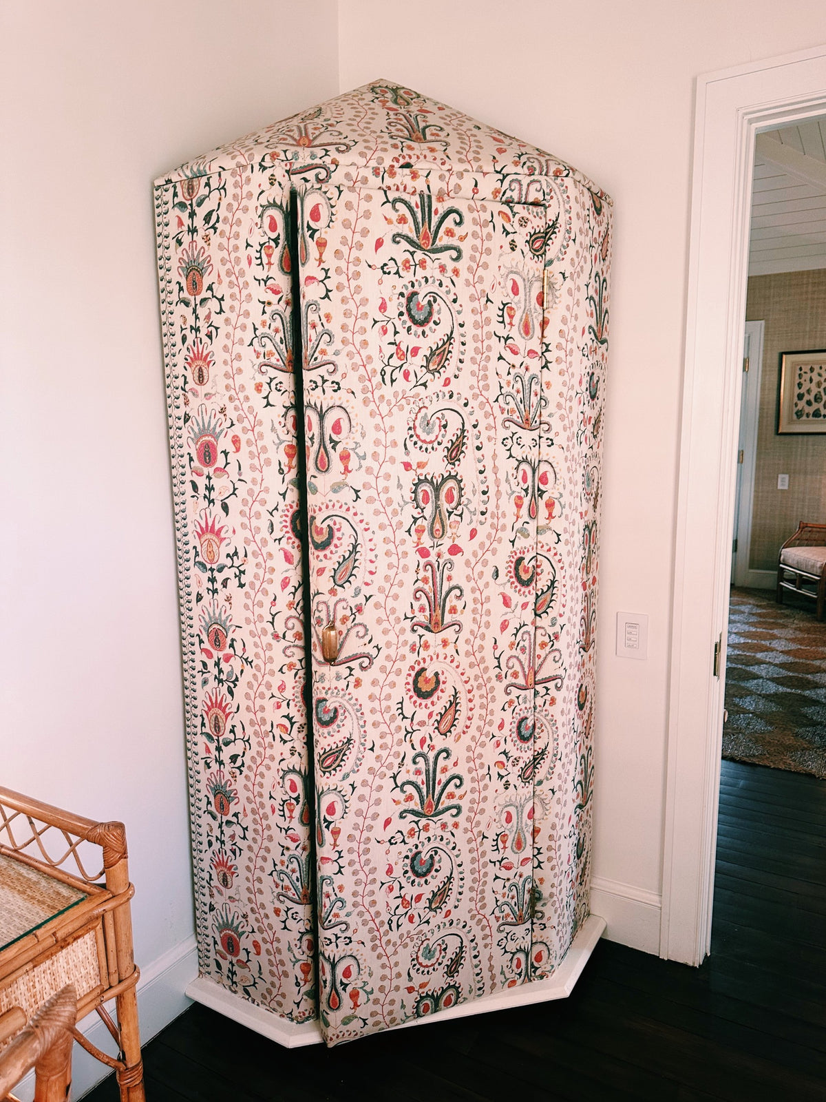 A corner cabinet covered in pink paisley fabric