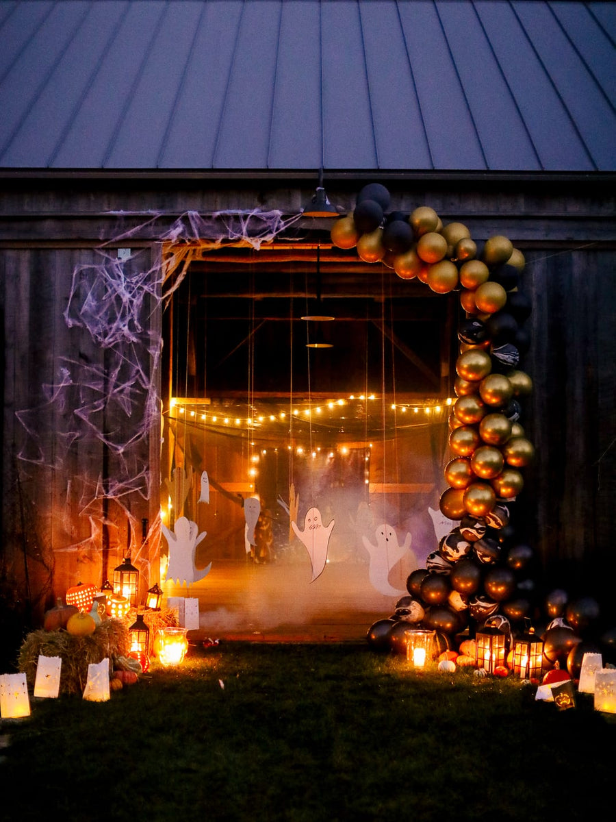 An old barn at dusk hung with cobwebs and black and gold balloons