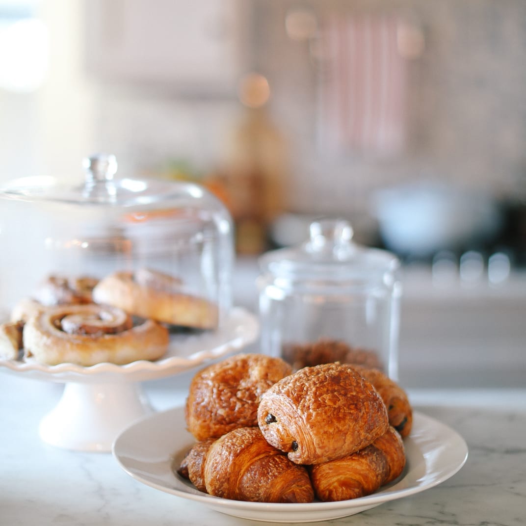 Croissants and pastries under glass cloches on a white cake stand