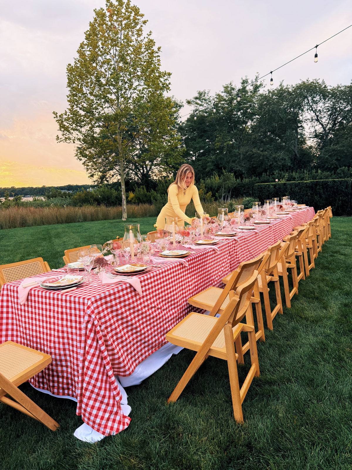 A long gingham table on the lawn at sunset