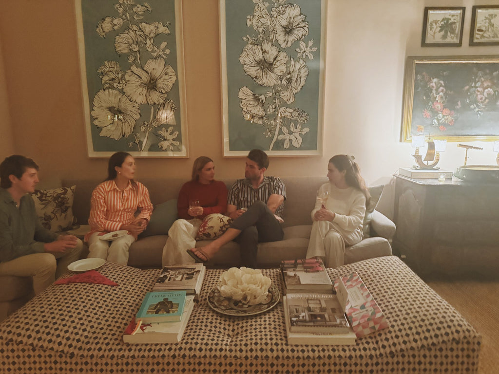 Everyone on the sofa after dinner, books and a bowl of flowers on the ottoman