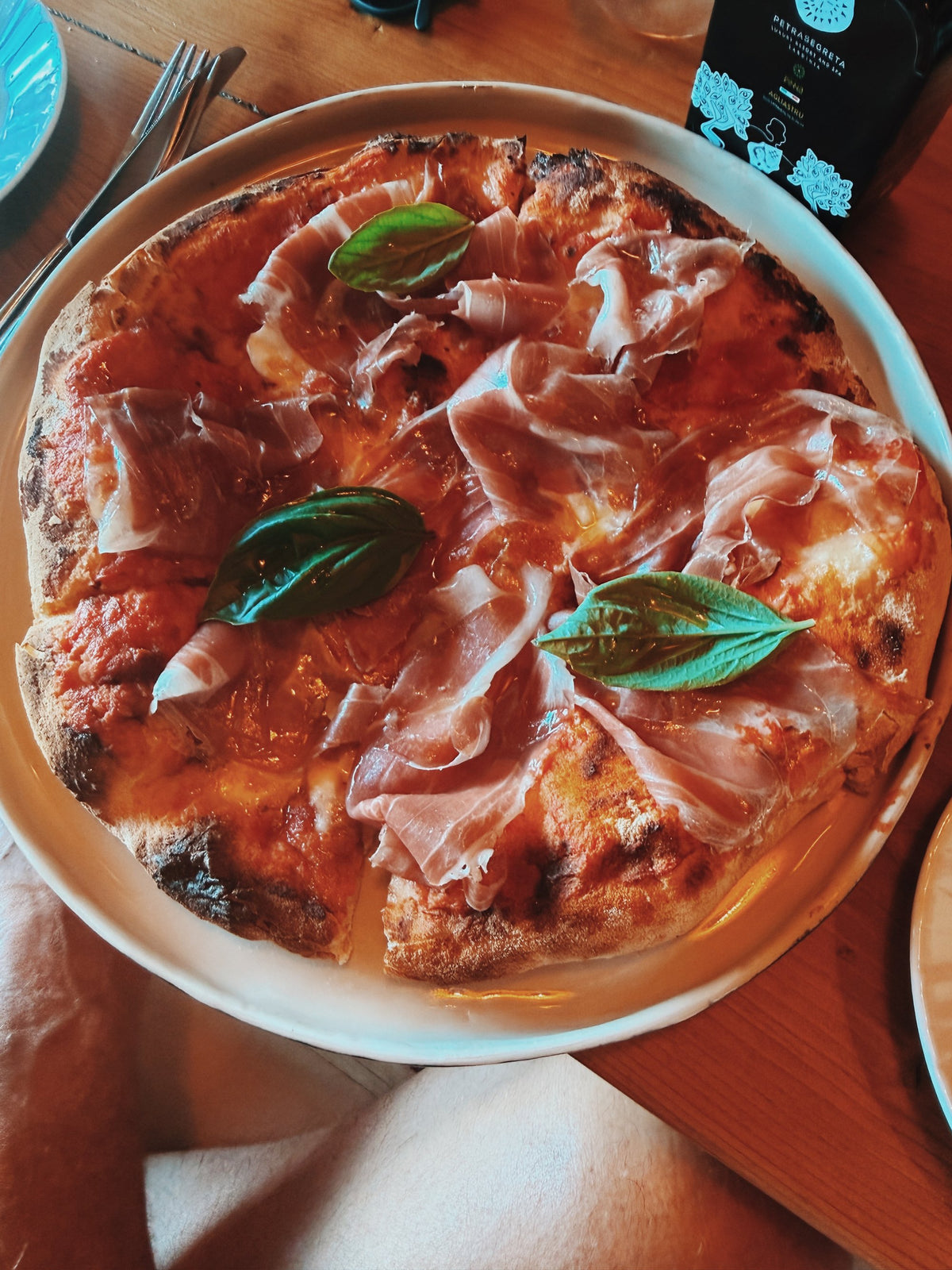 A pizza with prosciutto and basil