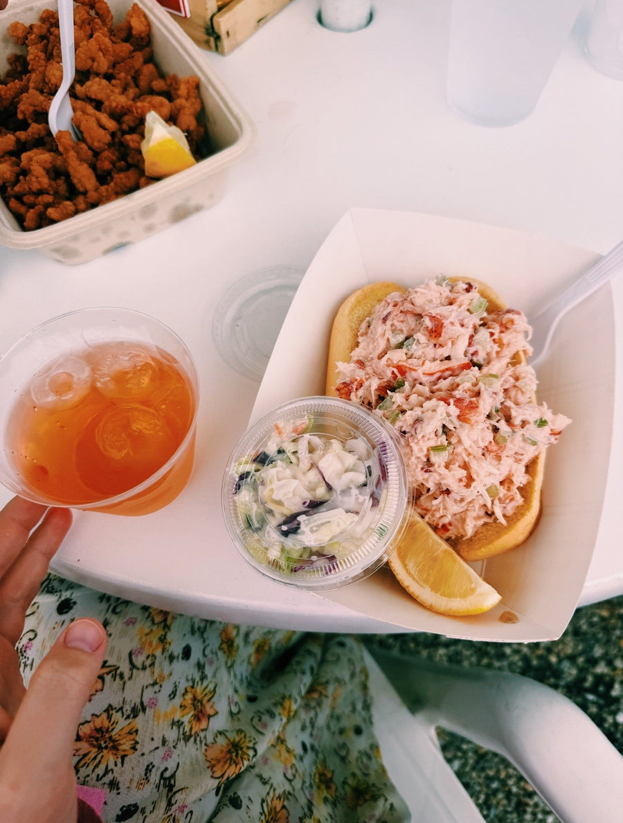 A lobster roll and an iced tea on a flowered cloth