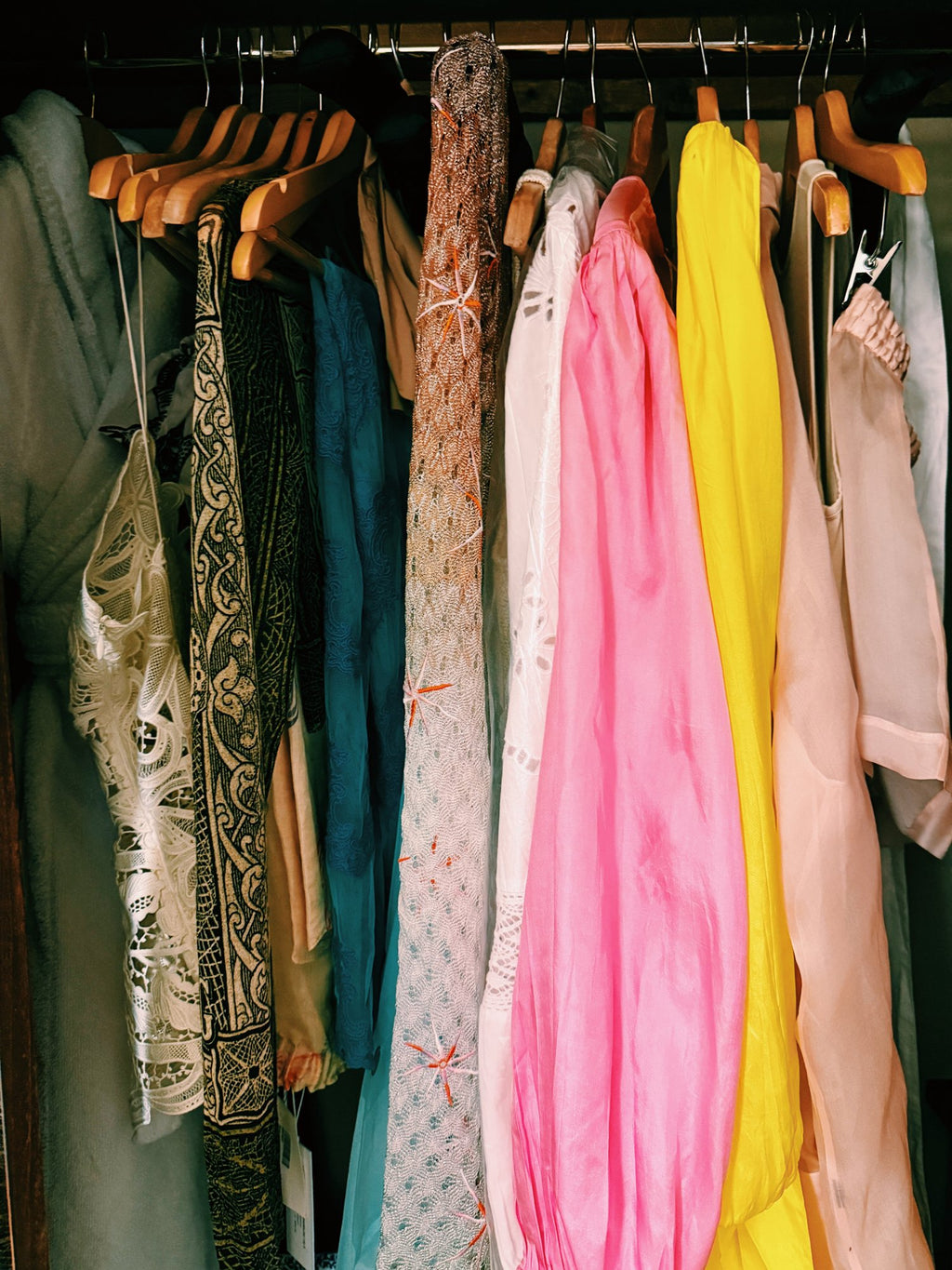 A rail of holiday clothes in pinks, yellow and white