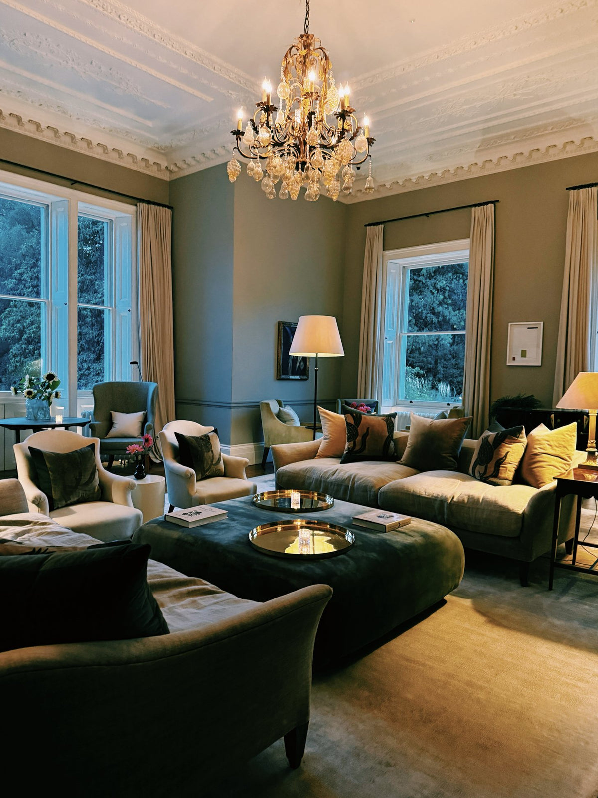 The drawing room at Heckfield Place, green sofas under a chandelier