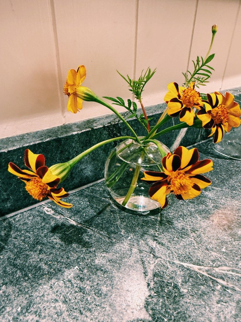 Orange lilies in a glass on a marble ledge