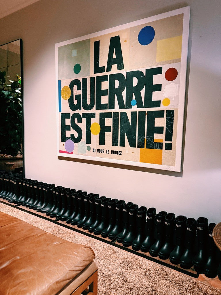 A poster that says La Guerre est Finie above a row of boots
