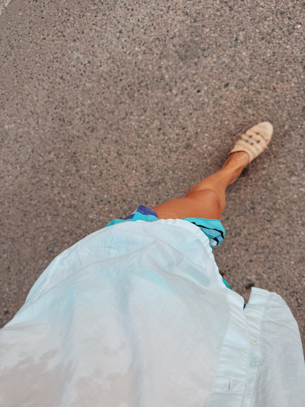 Woven sandals under a pale blue skirt