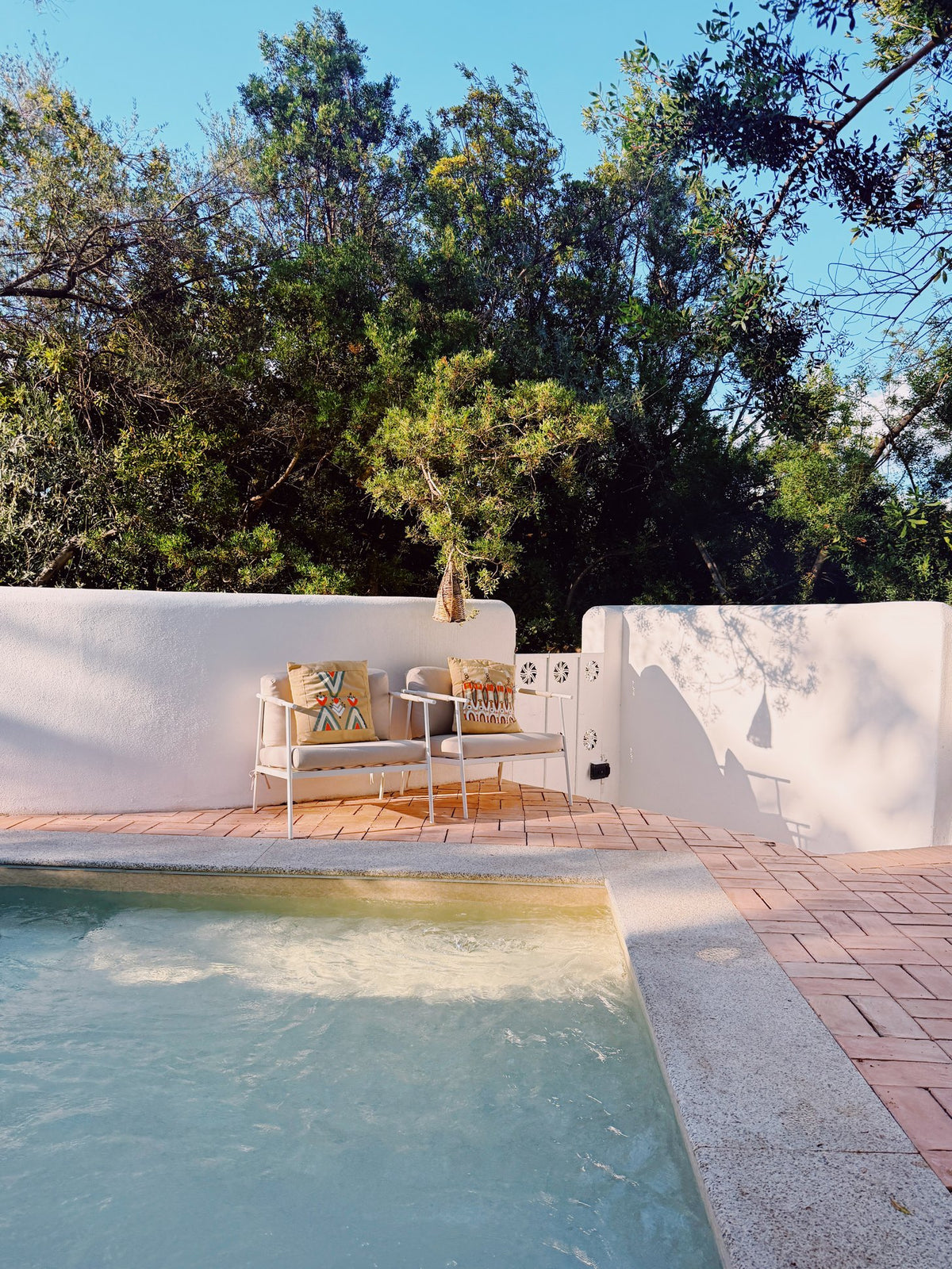 The pool at Su Gologone, whitewashed walls and olive trees