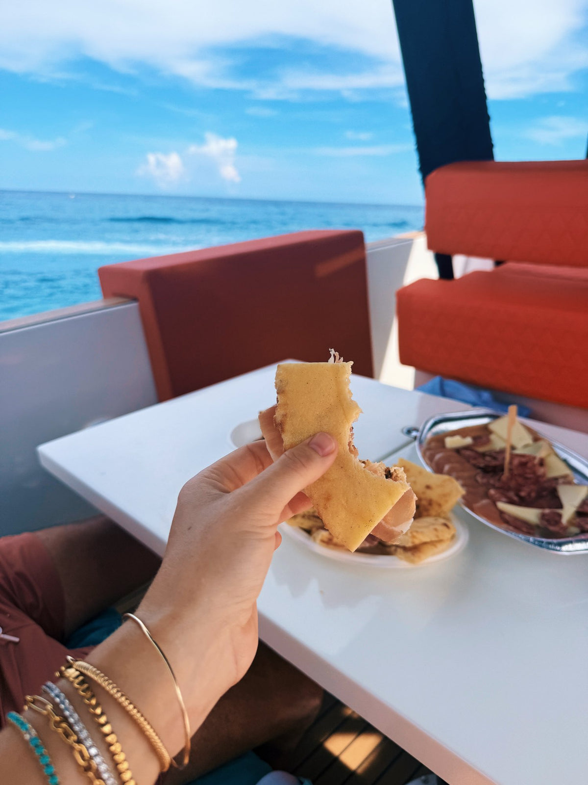 Bread and cheese at a table on the back of a boat, the sea behind