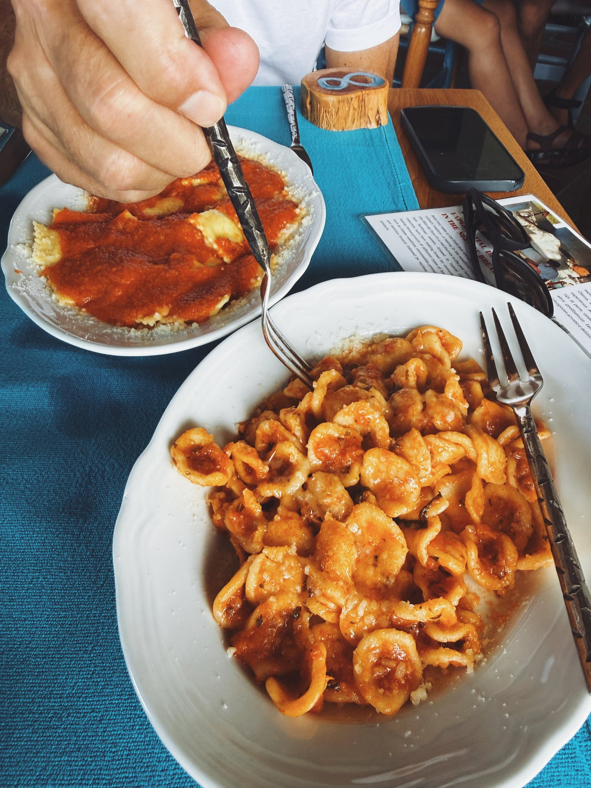 A plate of pasta with tomato sauce on a blue tablecloth