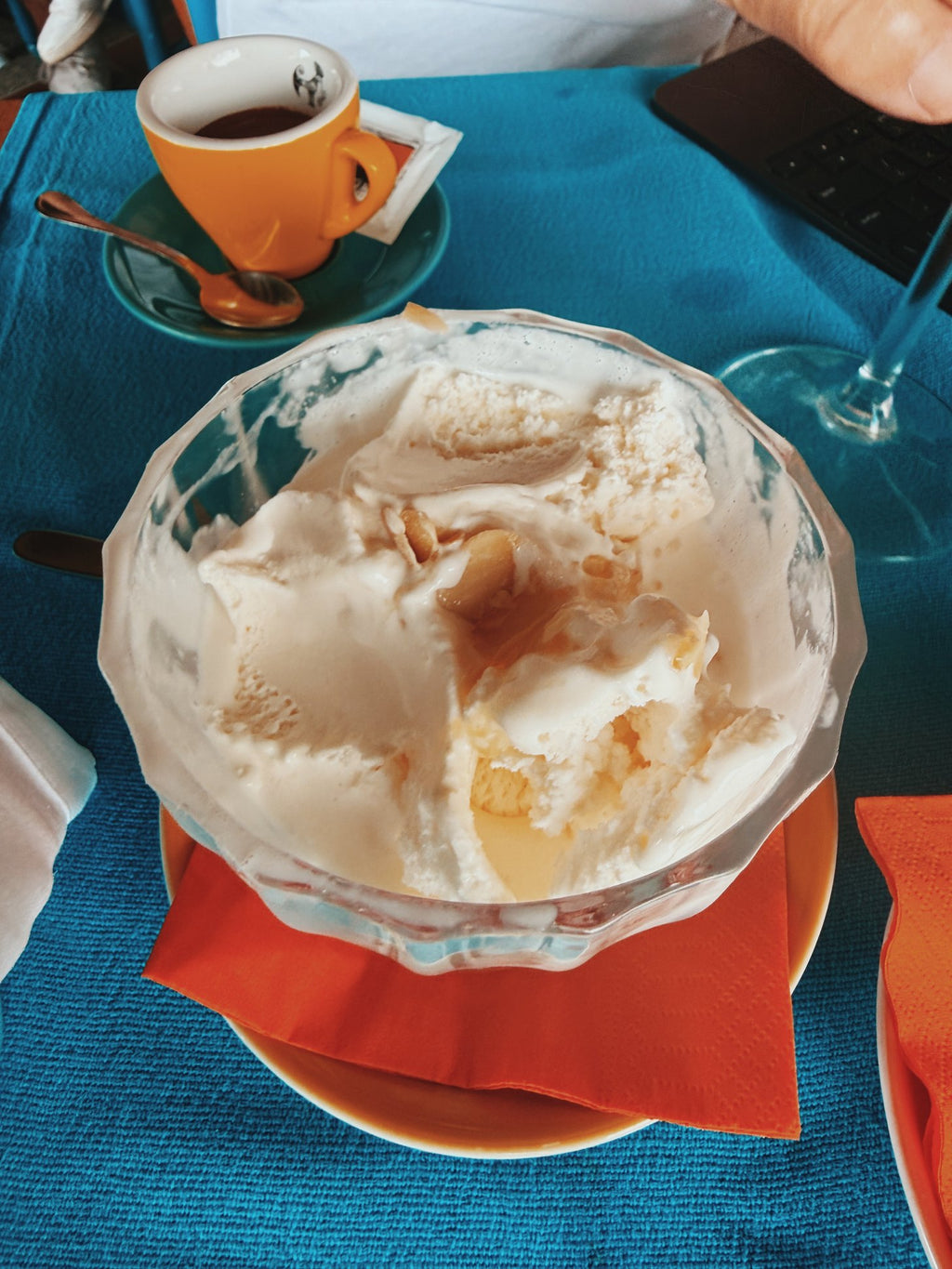 A coupe of ice cream beside an espresso on a blue cloth