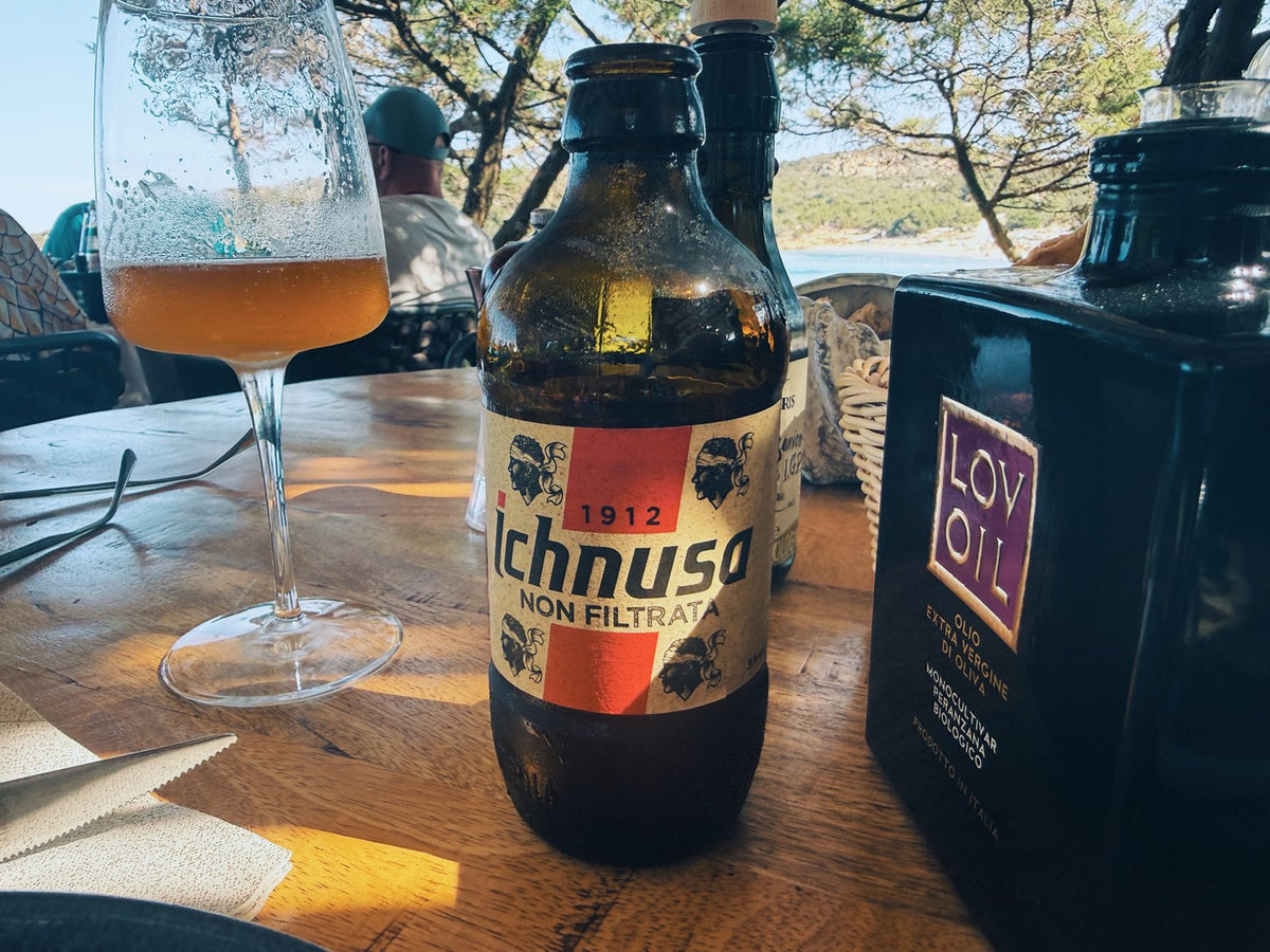 A bottle of Ichnusa and a glass of beer on a wooden table