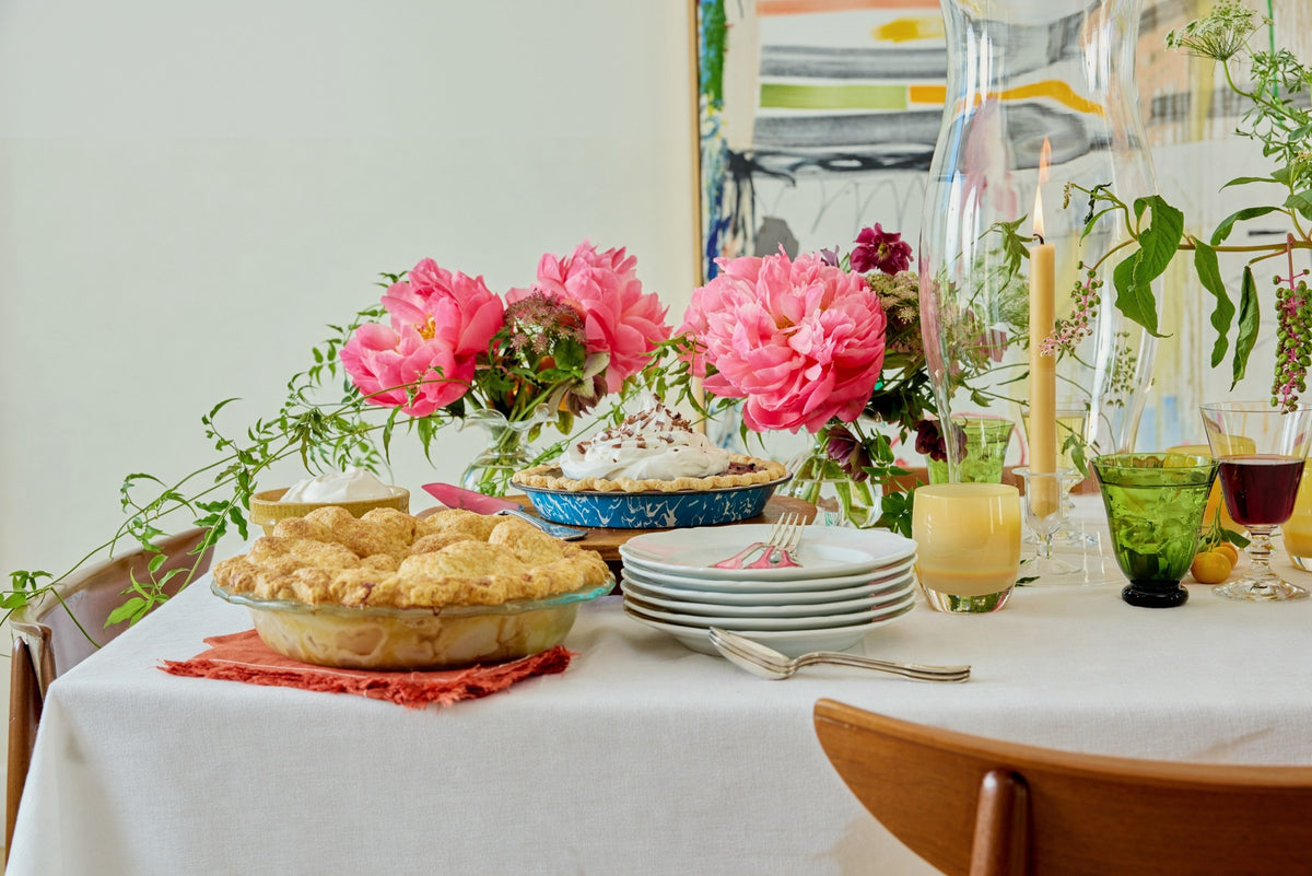 Coral peonies down the long table, pies and plates beneath