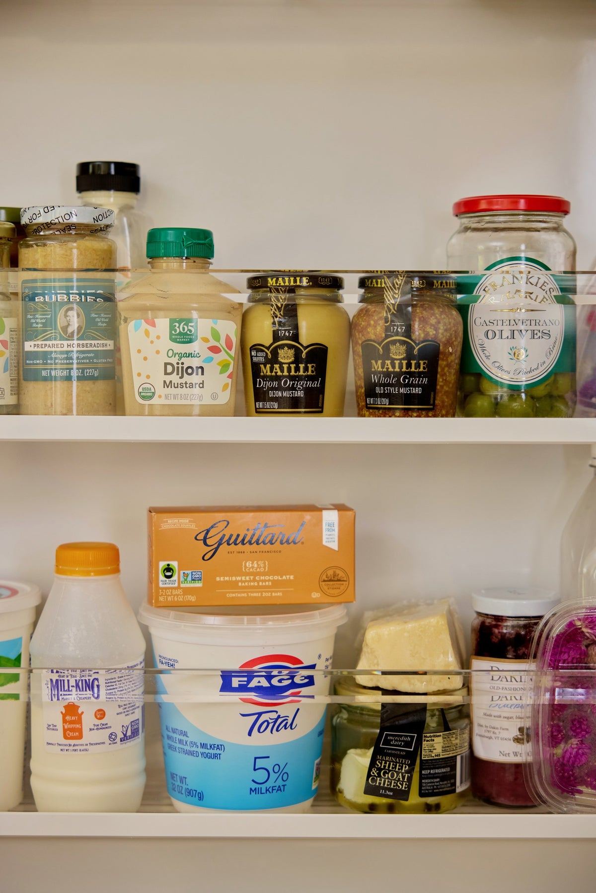 The fridge shelves: mustards, jars, yogurt and milk