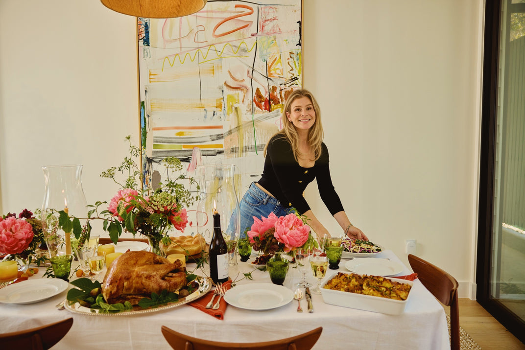 Lucy setting the Thanksgiving table, the turkey on its platter and peonies down the cloth