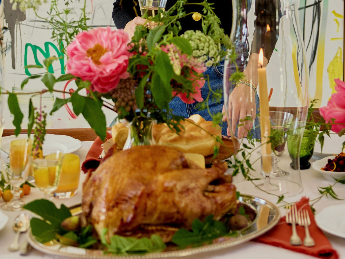 Our roast turkey on a silver platter with greens, peonies and tapers behind