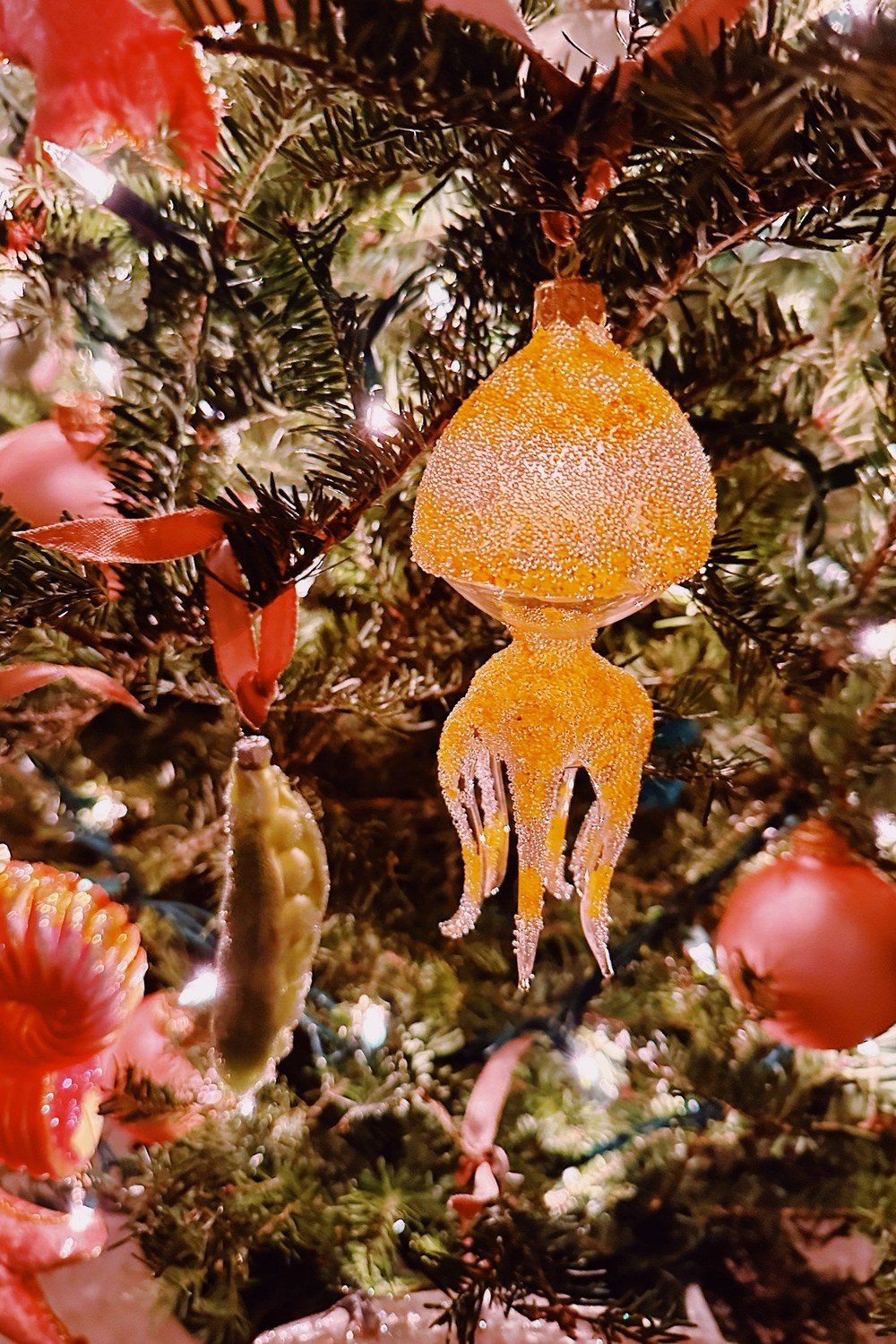 Glass ornaments on dark fir branches in candlelight