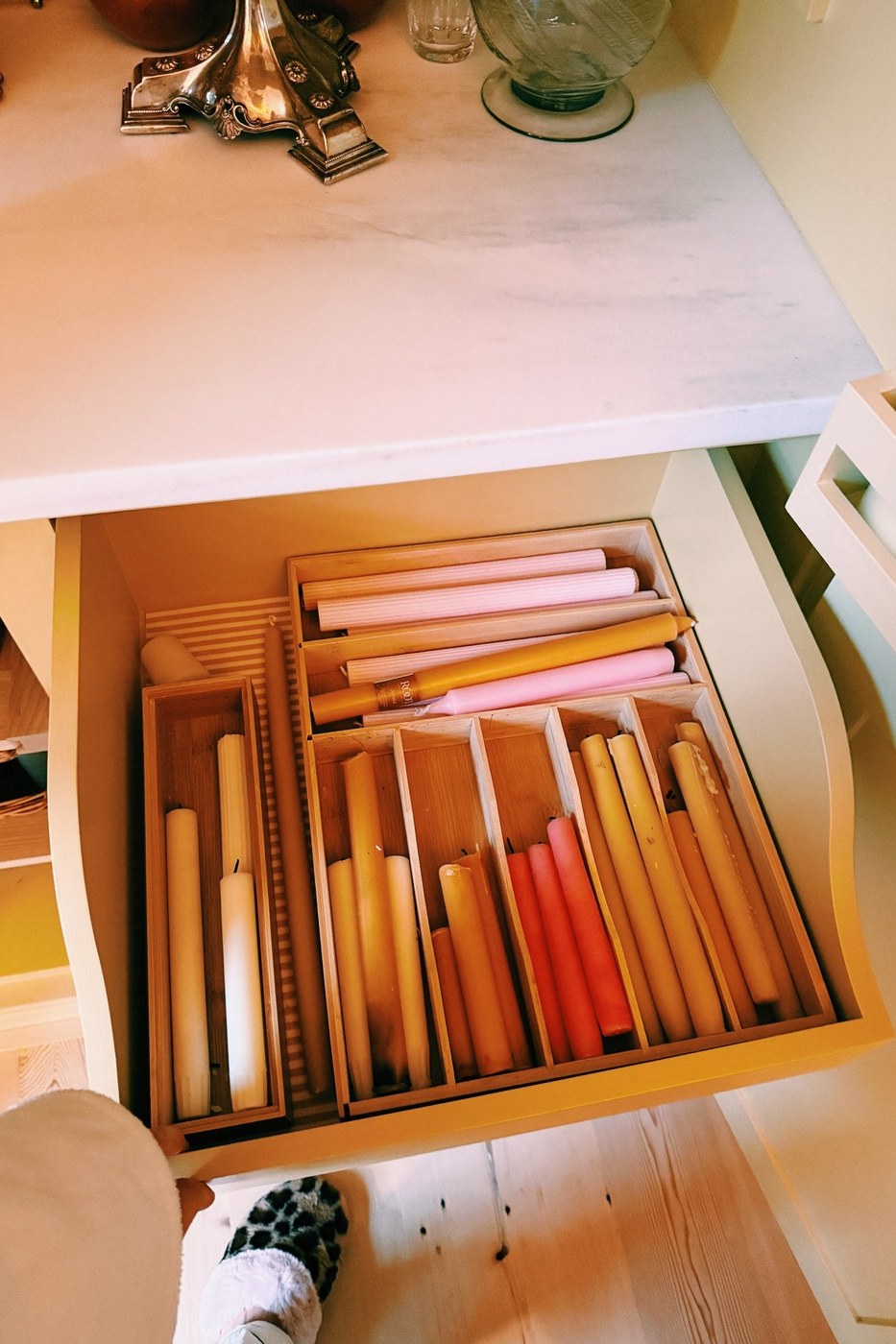 An open drawer of candles, sorted by color